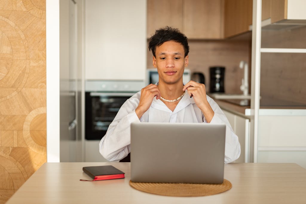 A young man in casual attire focuses on his laptop, creating a relaxed home office vibe.