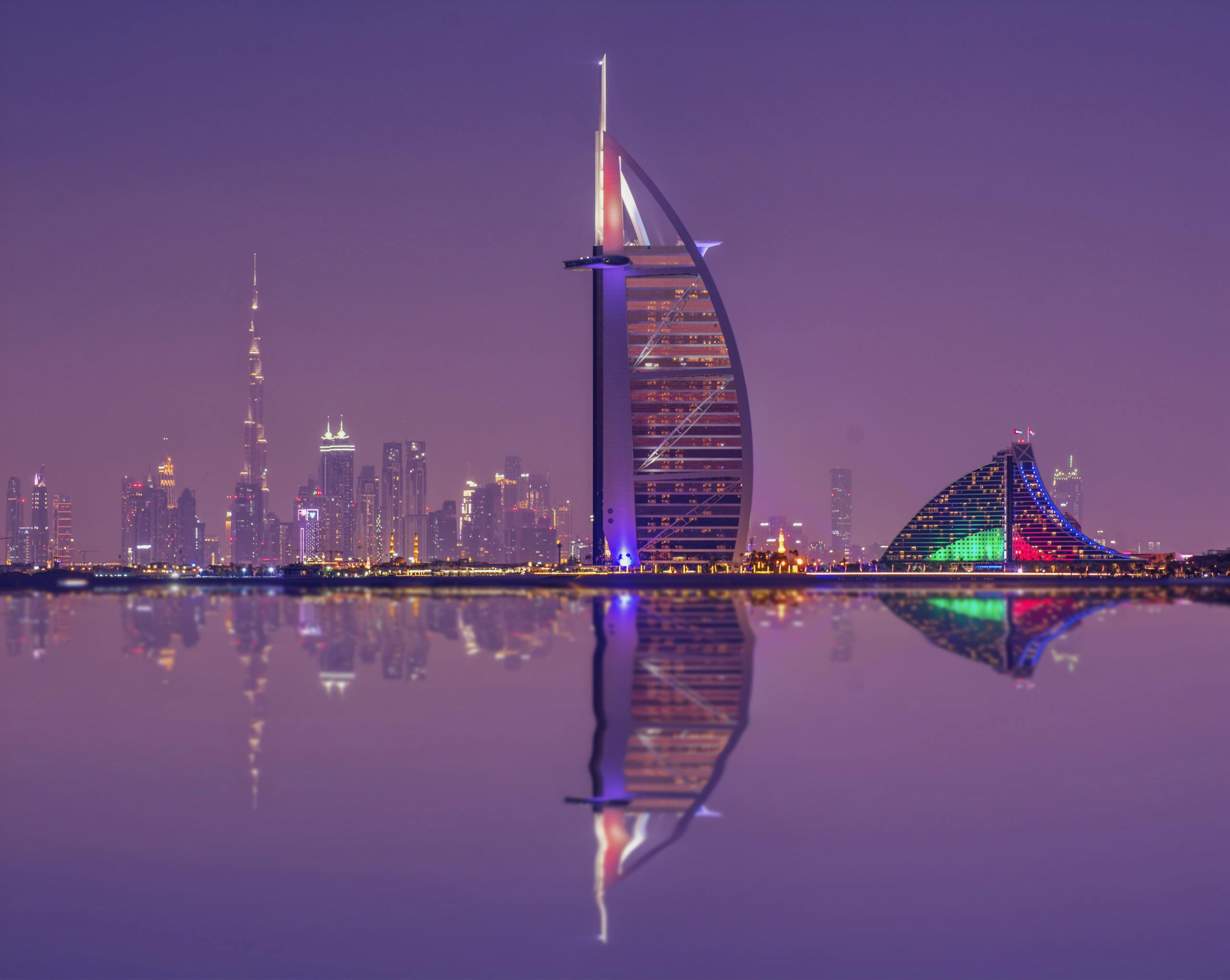 Captivating night scene showcasing Burj Al Arab and Dubai skyline reflections.