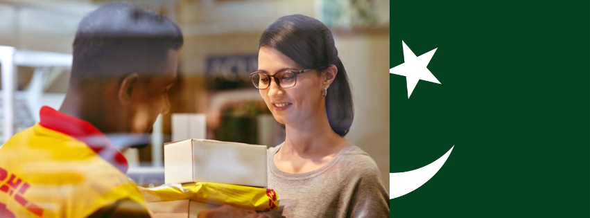 A man from DHL delivering a package to a woman and the Pakistan flag in the background
